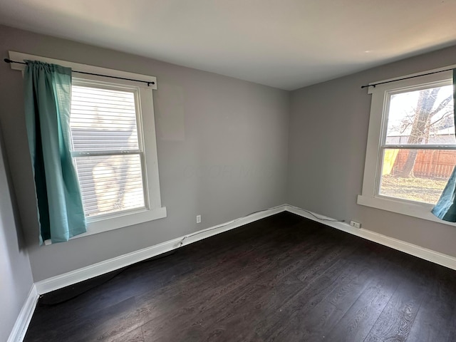 unfurnished room with baseboards and dark wood finished floors