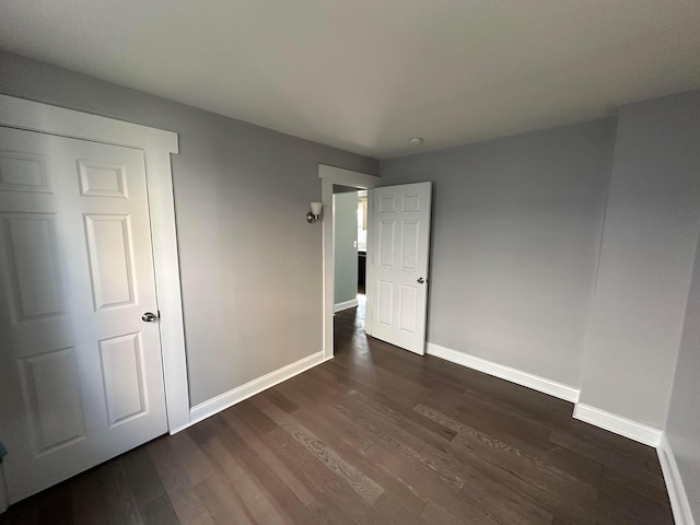 unfurnished bedroom featuring dark wood finished floors and baseboards