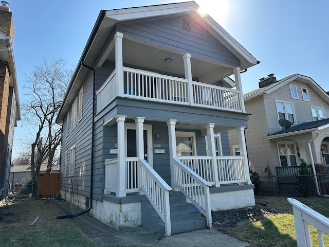 view of front facade with a balcony, a porch, and fence