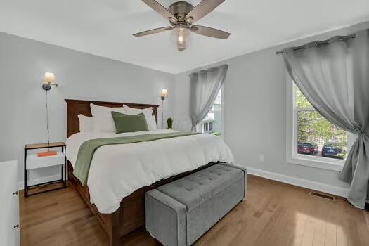 bedroom with wood finished floors, visible vents, a ceiling fan, and baseboards