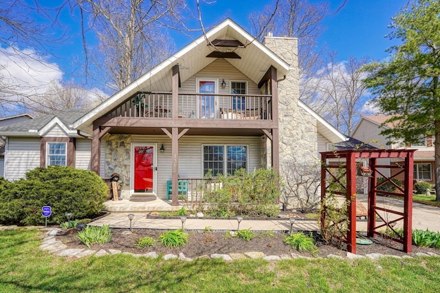 view of front of home with a porch, a balcony, and a chimney