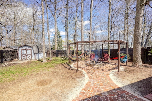 view of yard featuring a fenced backyard, an outdoor structure, an outdoor fire pit, and a storage unit