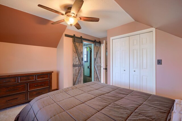 bedroom with ceiling fan, a closet, a barn door, light carpet, and lofted ceiling