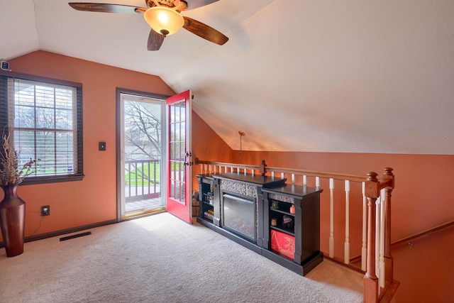 interior space with an upstairs landing, a ceiling fan, visible vents, lofted ceiling, and carpet