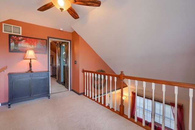 hallway with visible vents, baseboards, an upstairs landing, vaulted ceiling, and light colored carpet
