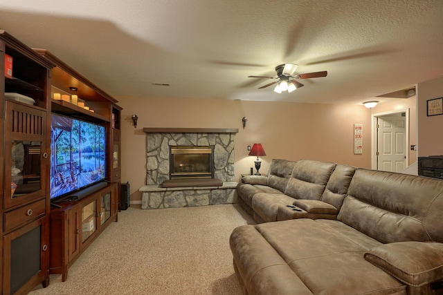 living room with visible vents, a ceiling fan, a textured ceiling, a fireplace, and light colored carpet