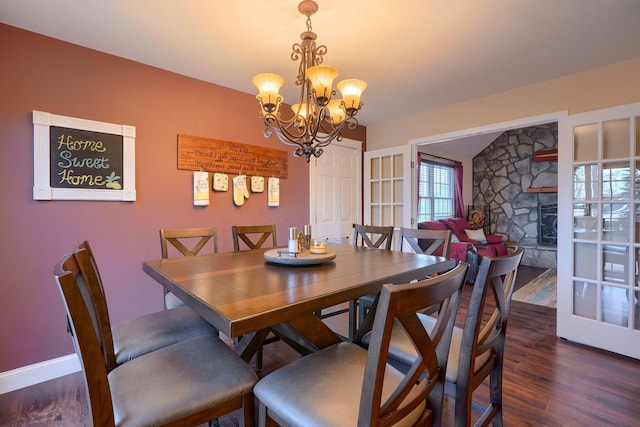 dining area featuring baseboards, a notable chandelier, wood finished floors, and a fireplace