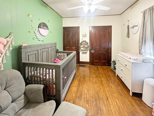 113 Chestnut St SE, Corning, OH 43730 - bedroom with light wood finished floors, a crib, and ceiling fan