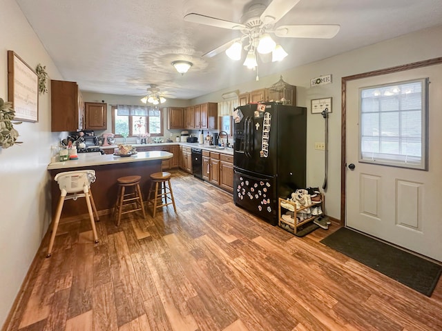 113 Chestnut St SE, Corning, OH 43730 - kitchen featuring light countertops, light wood finished floors, ceiling fan, a peninsula, and black appliances