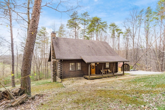 26063 Twin Fls, Rockbridge, OH 43149 - view of front of house featuring a wooden deck, log siding, roof with shingles, and a chimney