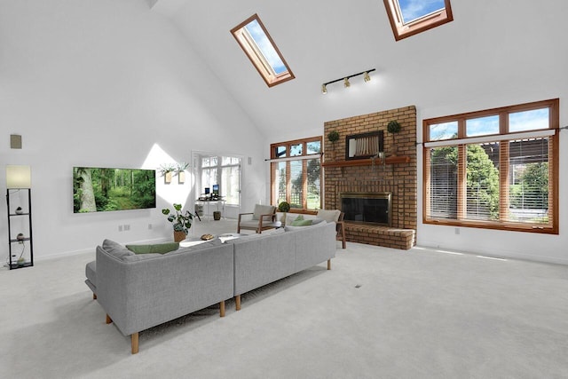 carpeted living room featuring baseboards, high vaulted ceiling, a skylight, and a fireplace