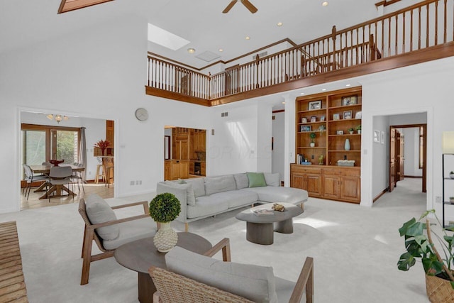 carpeted living room featuring a high ceiling, baseboards, recessed lighting, a ceiling fan, and a skylight
