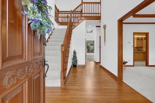 entrance foyer featuring stairs, light wood-style floors, and baseboards