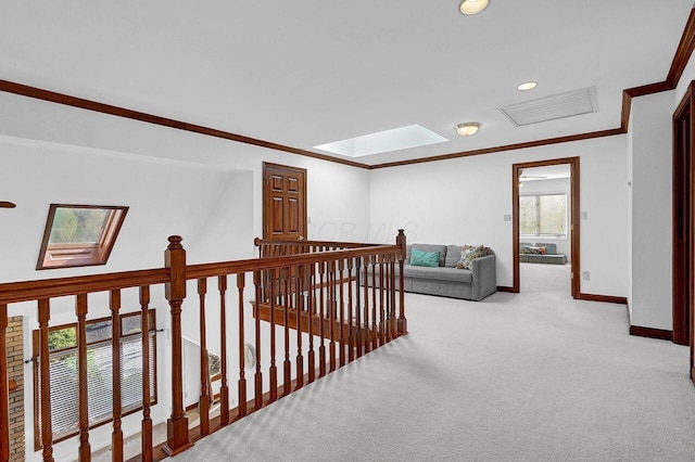 corridor featuring baseboards, a skylight, carpet floors, and crown molding