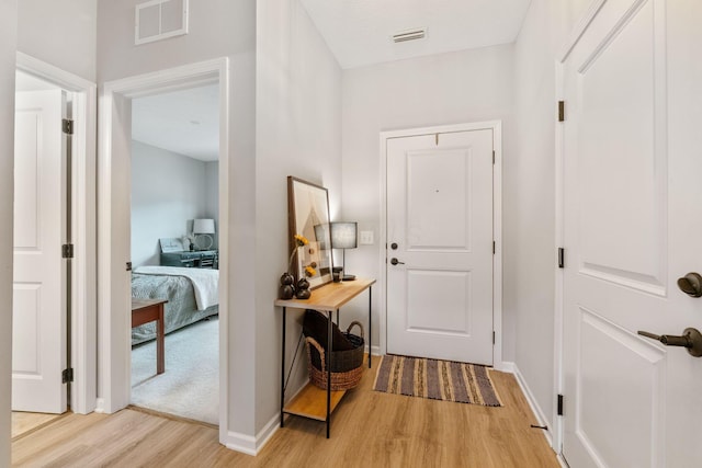 corridor with baseboards, visible vents, and light wood-style floors