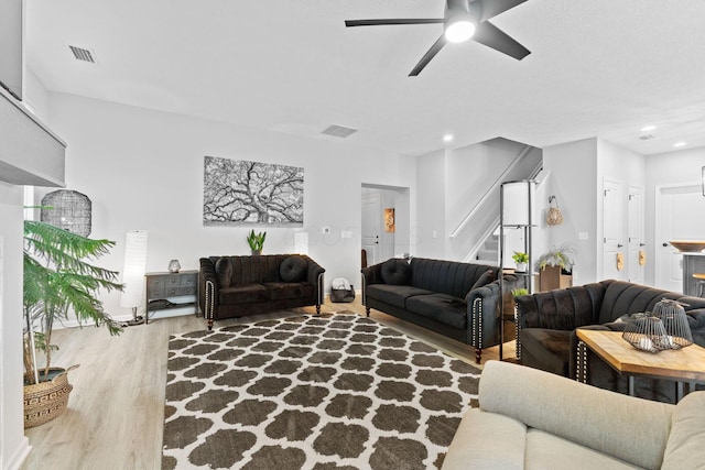 living area featuring visible vents, wood finished floors, stairway, and a ceiling fan