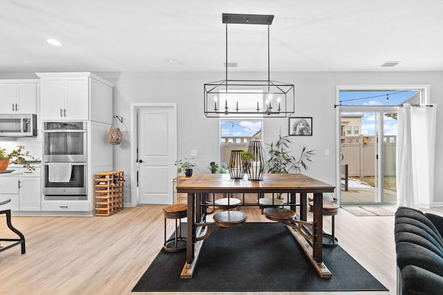 dining room with visible vents, an inviting chandelier, light wood-type flooring, and plenty of natural light
