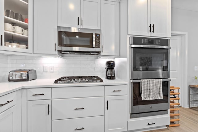 kitchen with white cabinetry, tasteful backsplash, light wood-style flooring, and stainless steel appliances