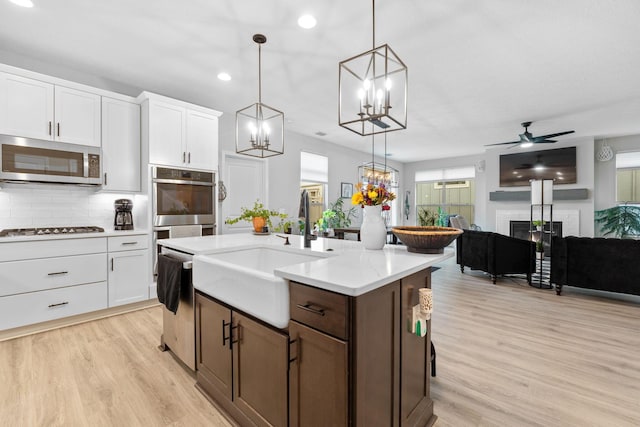 kitchen with light countertops, backsplash, a glass covered fireplace, open floor plan, and stainless steel appliances