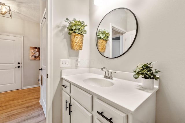 bathroom with vanity, a textured ceiling, baseboards, and wood finished floors