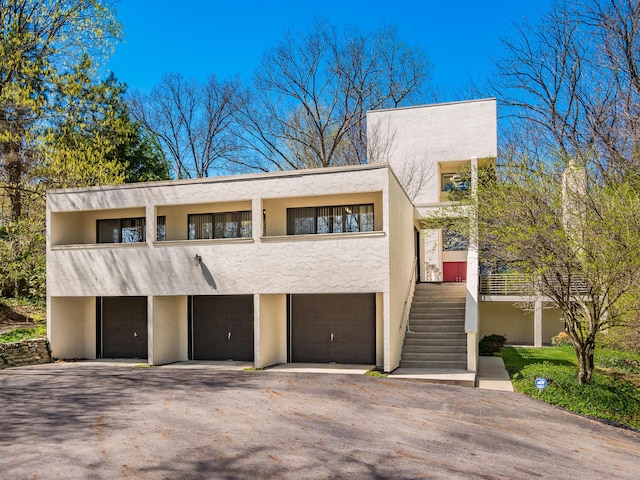 view of front of home with a garage, stucco siding, aphalt driveway, and stairs