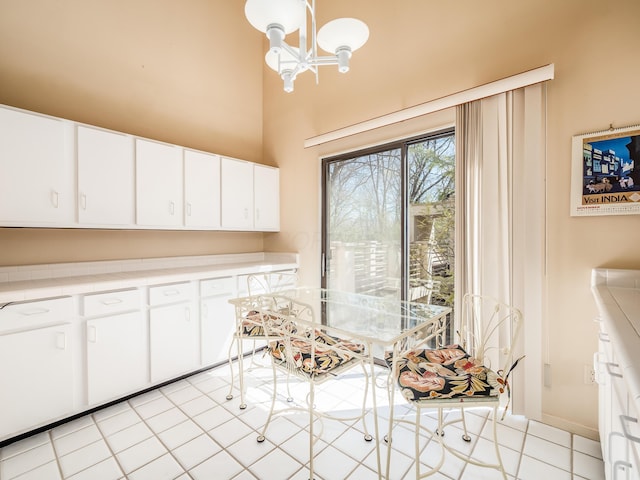 dining space with a chandelier, a towering ceiling, and light tile patterned flooring