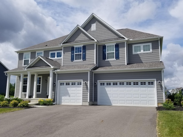 view of front of home featuring driveway, a garage, and roof with shingles