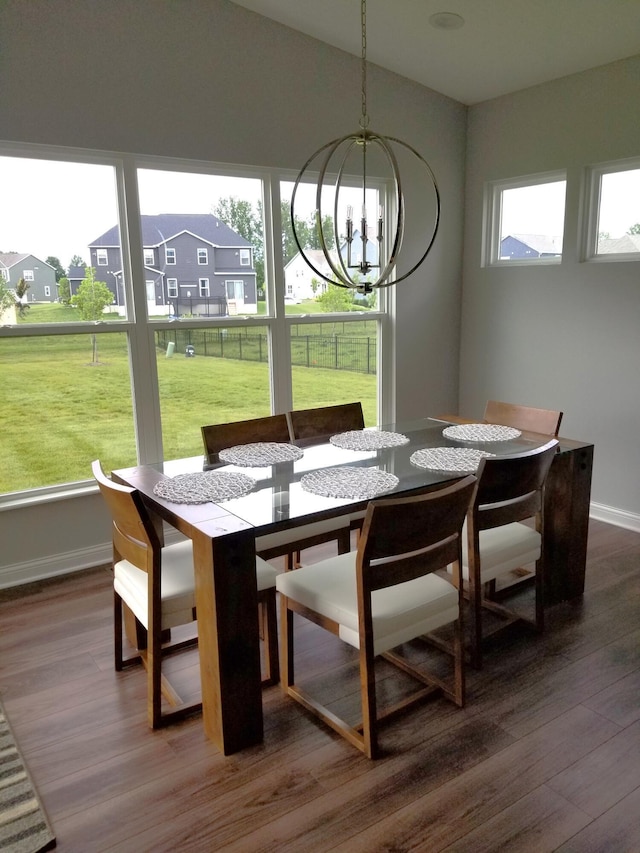 dining space with baseboards, wood finished floors, a residential view, vaulted ceiling, and a notable chandelier
