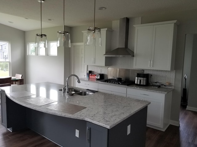 kitchen with wall chimney exhaust hood, tasteful backsplash, a sink, dark wood-style floors, and gas stovetop