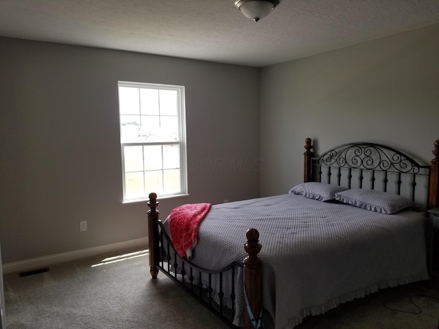 bedroom with baseboards, a textured ceiling, visible vents, and carpet