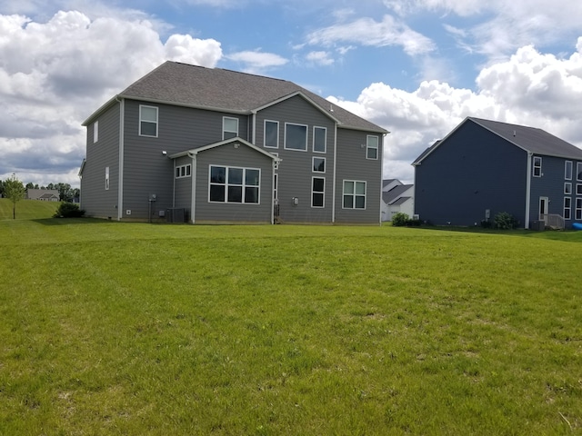 rear view of property with central AC unit and a lawn