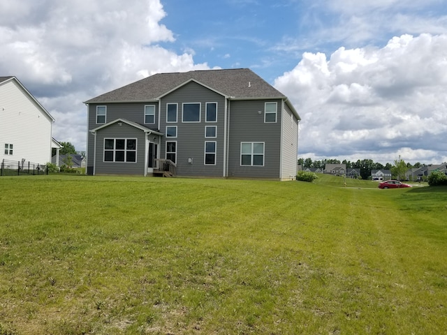 rear view of property with a lawn and a shingled roof