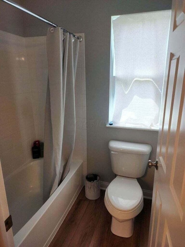 full bath featuring baseboards, toilet, shower / tub combo, and wood finished floors