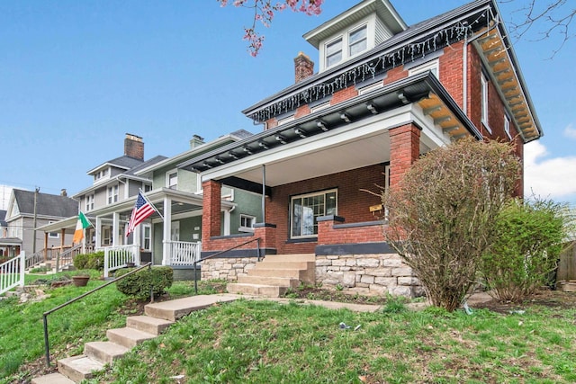 traditional style home with brick siding, a porch, and a front yard