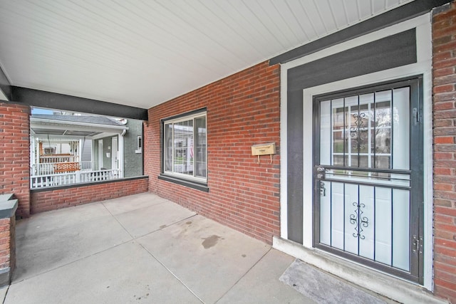 exterior space with covered porch, brick siding, and an attached carport