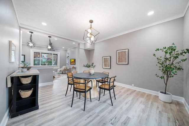 dining space featuring light wood-style flooring, crown molding, and baseboards