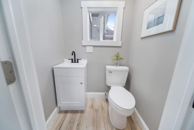 bathroom featuring baseboards, toilet, vanity, and wood finished floors