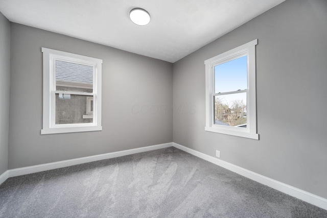carpeted empty room featuring baseboards