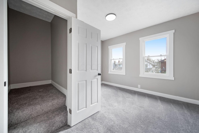 unfurnished room featuring carpet floors and baseboards