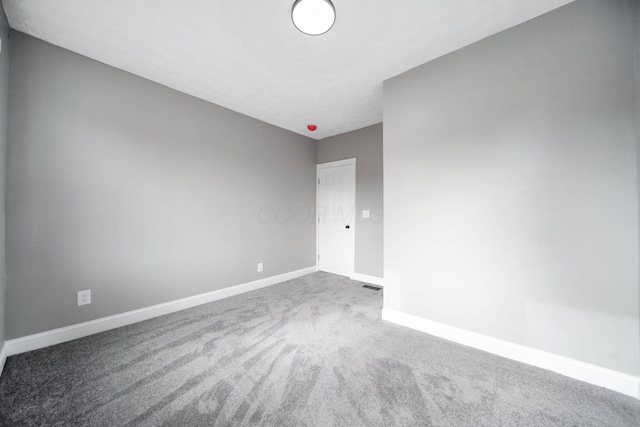 carpeted empty room featuring baseboards