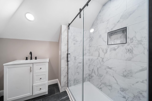 bathroom featuring baseboards, lofted ceiling, vanity, and a marble finish shower