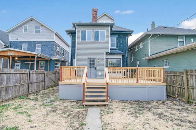 rear view of property with a chimney, a wooden deck, and fence