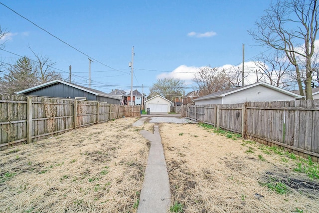 view of yard with a fenced backyard, an outbuilding, and a detached garage