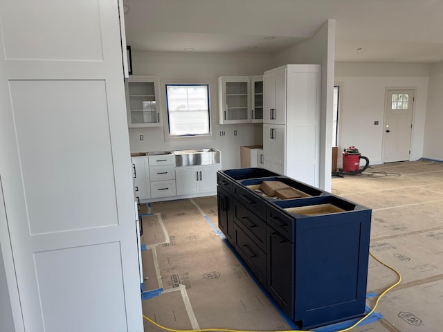 kitchen featuring glass insert cabinets, a center island, and white cabinetry