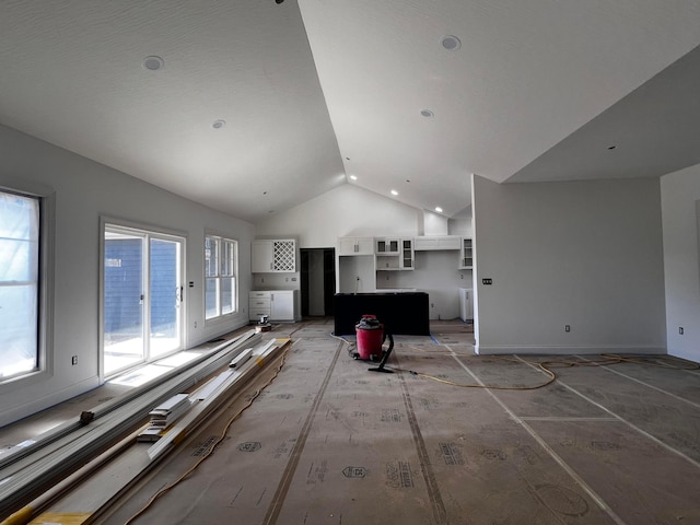 unfurnished living room featuring baseboards and high vaulted ceiling