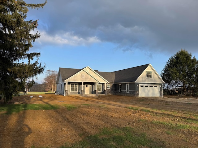 craftsman-style home with an attached garage, driveway, stone siding, and a porch