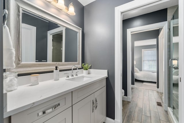 bathroom with baseboards, toilet, connected bathroom, wood finish floors, and vanity