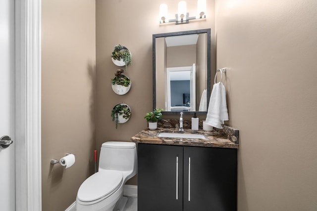bathroom with toilet, vanity, and baseboards