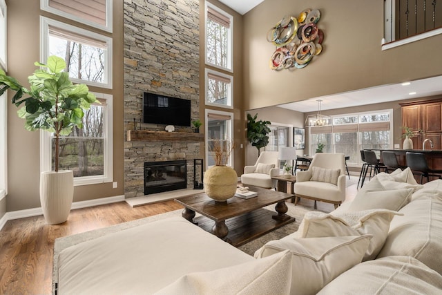 living room featuring a healthy amount of sunlight, a stone fireplace, and wood finished floors