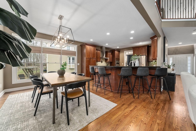 dining room with a chandelier, recessed lighting, light wood finished floors, and baseboards